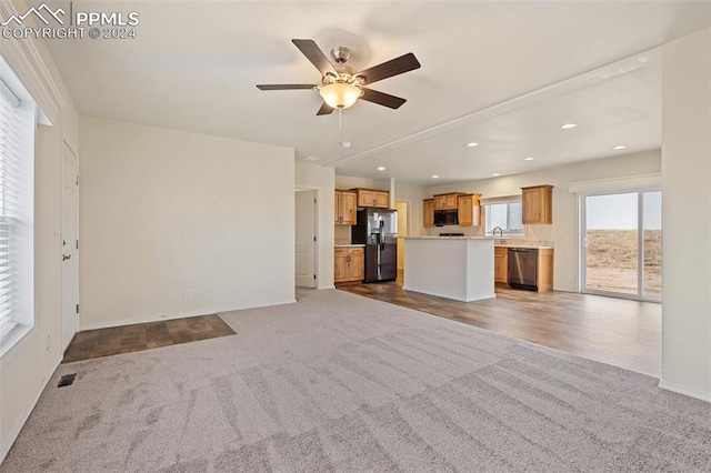 unfurnished living room featuring dark carpet, ceiling fan, and sink