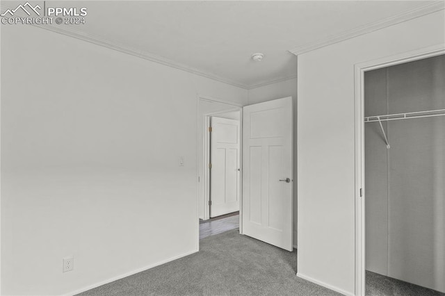 unfurnished bedroom with dark carpet, ornamental molding, and a closet