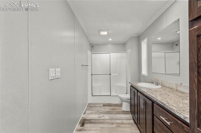 bathroom with toilet, hardwood / wood-style flooring, oversized vanity, a shower with door, and crown molding