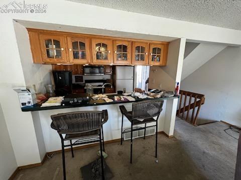 kitchen featuring white fridge, a breakfast bar, vaulted ceiling, and a textured ceiling