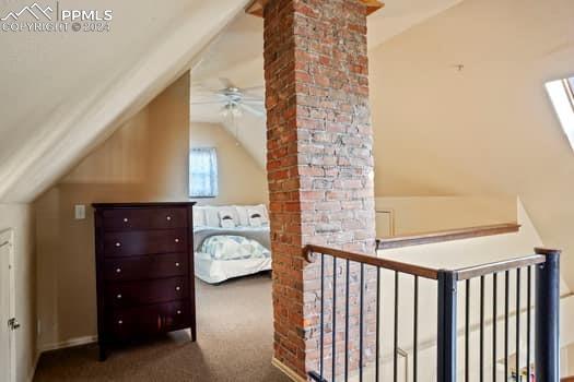 additional living space with ceiling fan, brick wall, dark carpet, and vaulted ceiling