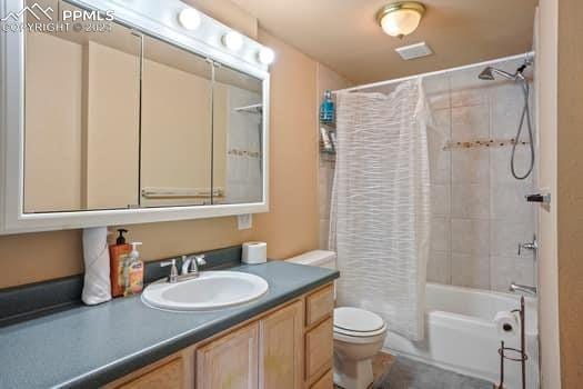 full bathroom with toilet, vanity, and shower / tub combo with curtain