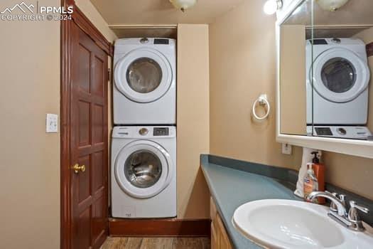 washroom featuring stacked washer and clothes dryer, dark hardwood / wood-style floors, and sink