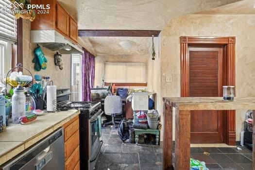 kitchen featuring stainless steel appliances, a healthy amount of sunlight, tile countertops, and dark tile floors