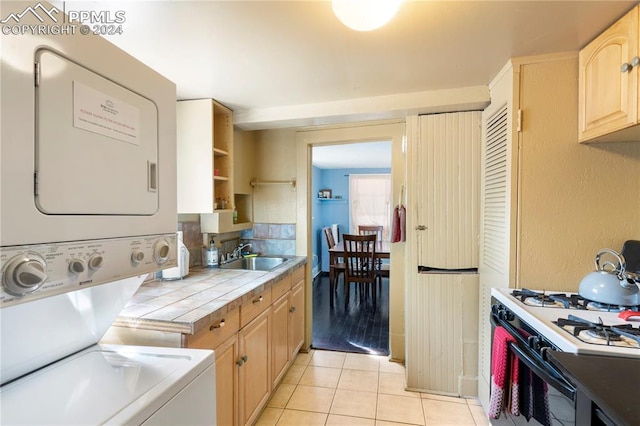 interior space with light brown cabinetry, tile counters, sink, white range oven, and light tile floors