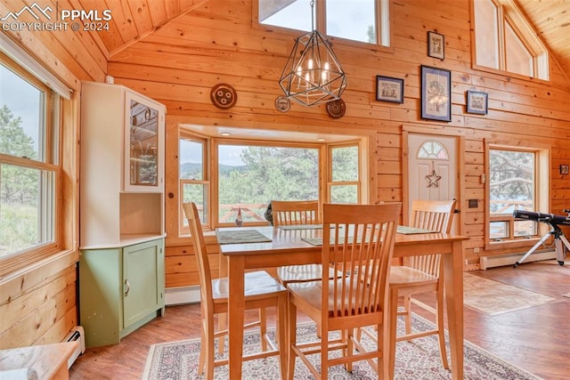 dining area with wooden walls, a baseboard radiator, a chandelier, wood ceiling, and light hardwood / wood-style floors