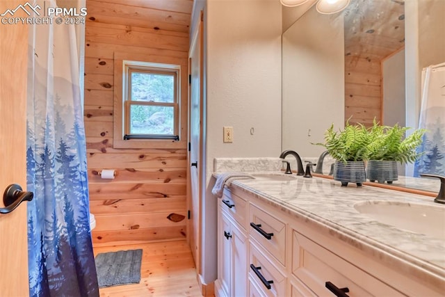 bathroom featuring wood walls, double vanity, and hardwood / wood-style floors