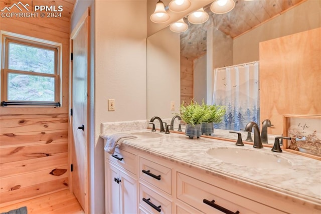 bathroom featuring double sink vanity, hardwood / wood-style floors, vaulted ceiling, and wooden walls