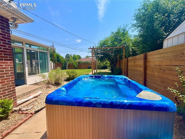 view of swimming pool featuring a hot tub and a sunroom