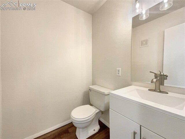 bathroom with toilet, vanity, and wood-type flooring