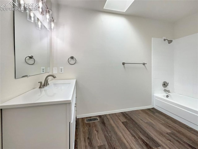 bathroom with a skylight, vanity with extensive cabinet space, shower / bathing tub combination, and wood-type flooring