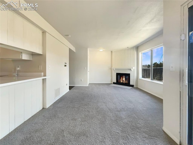 unfurnished living room with dark colored carpet