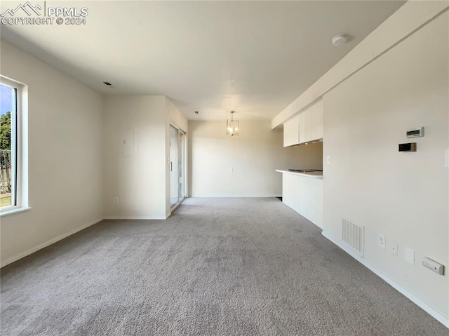 spare room with a notable chandelier and light carpet