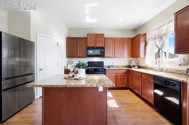 kitchen featuring a kitchen island, sink, light hardwood / wood-style flooring, and black appliances