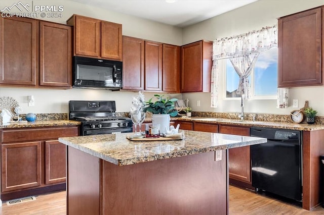 kitchen with light hardwood / wood-style floors, a kitchen island, and black appliances