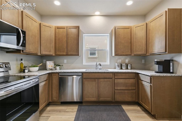 kitchen with light stone counters, sink, light wood-type flooring, and appliances with stainless steel finishes