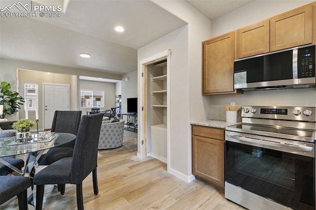 kitchen featuring light stone countertops, appliances with stainless steel finishes, and light hardwood / wood-style flooring