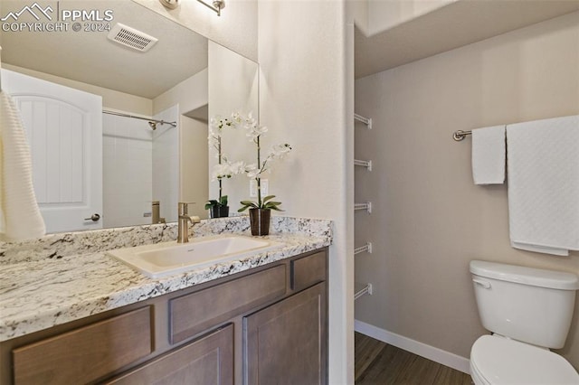 bathroom featuring a shower, vanity, hardwood / wood-style flooring, and toilet