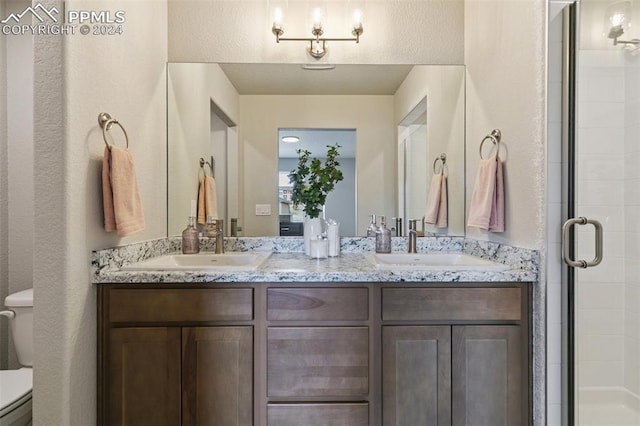 bathroom featuring a shower with door, vanity, and toilet