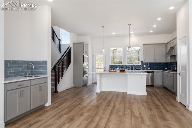 kitchen featuring sink, a center island, hanging light fixtures, stainless steel appliances, and gray cabinets