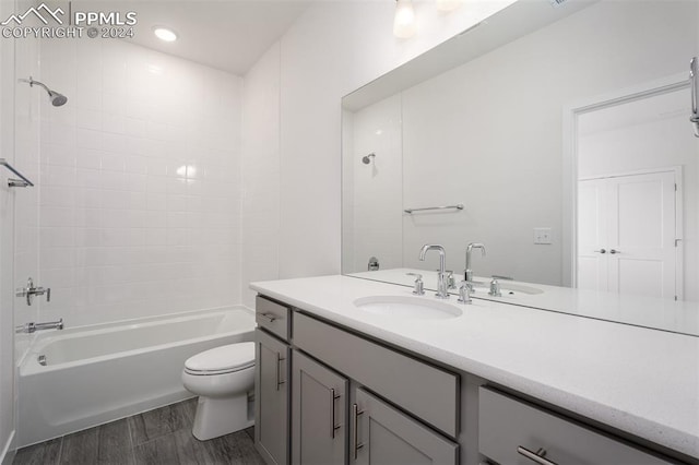 full bathroom featuring vanity, tiled shower / bath combo, and toilet