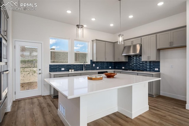 kitchen with hardwood / wood-style floors, pendant lighting, a center island, and sink