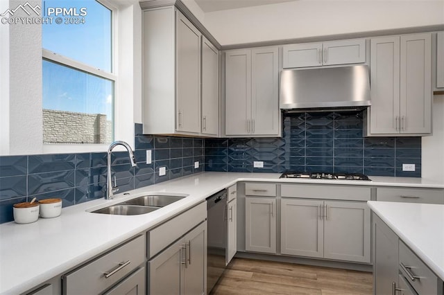 kitchen featuring backsplash, dishwasher, sink, and exhaust hood