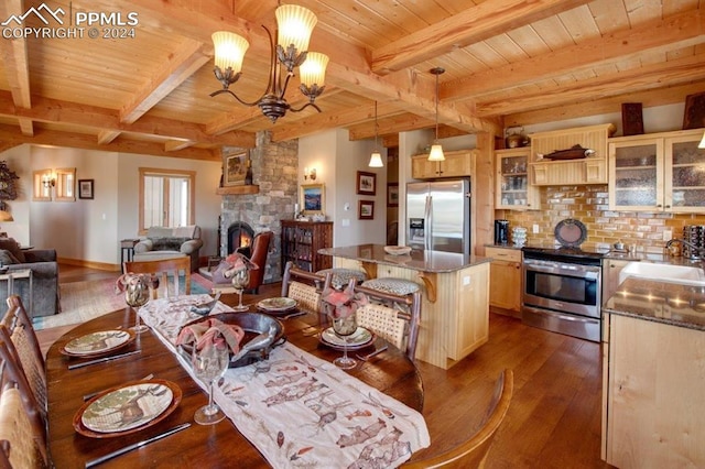 dining space with wooden ceiling, an inviting chandelier, dark wood-type flooring, a stone fireplace, and sink