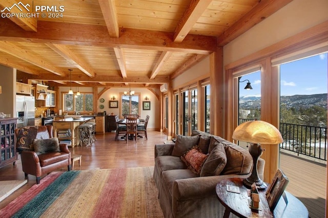 living room with beamed ceiling, a notable chandelier, a mountain view, hardwood / wood-style flooring, and wooden ceiling