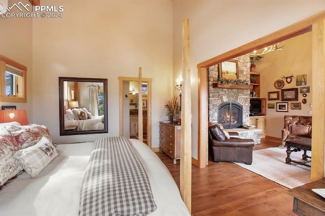 bedroom featuring a high ceiling, a fireplace, and light hardwood / wood-style flooring