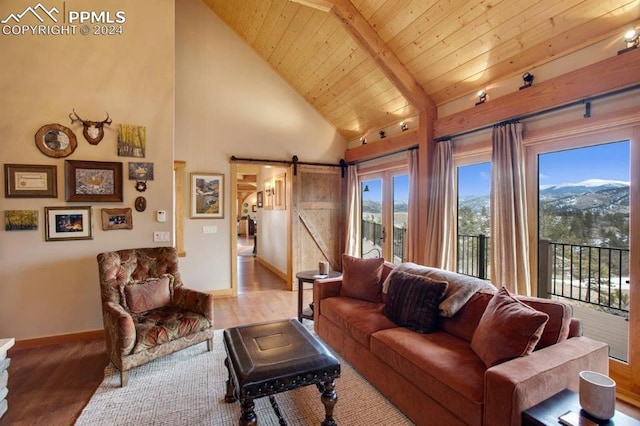 living room featuring light hardwood / wood-style floors, high vaulted ceiling, beam ceiling, a barn door, and wooden ceiling