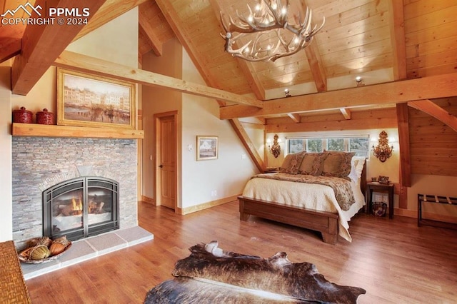 bedroom with lofted ceiling with beams, a fireplace, an inviting chandelier, and wood-type flooring