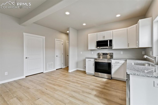 kitchen featuring appliances with stainless steel finishes, light wood-type flooring, light stone counters, sink, and white cabinetry