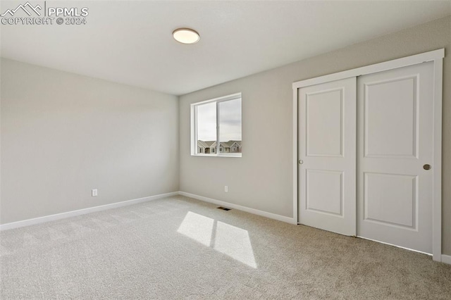 unfurnished bedroom featuring light carpet and a closet