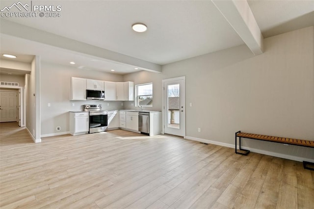 kitchen with sink, light hardwood / wood-style flooring, beamed ceiling, white cabinetry, and stainless steel appliances