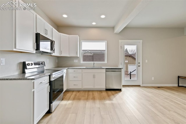 kitchen featuring light wood-type flooring, stainless steel appliances, sink, beamed ceiling, and white cabinetry