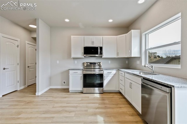 kitchen with white cabinetry, sink, stainless steel appliances, and light hardwood / wood-style flooring