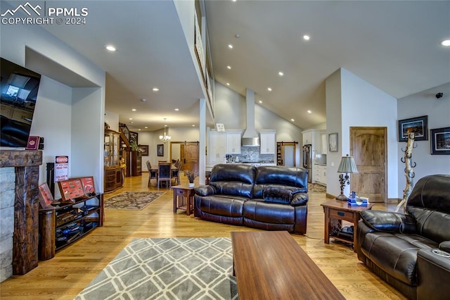 living room featuring a notable chandelier, high vaulted ceiling, and light hardwood / wood-style floors