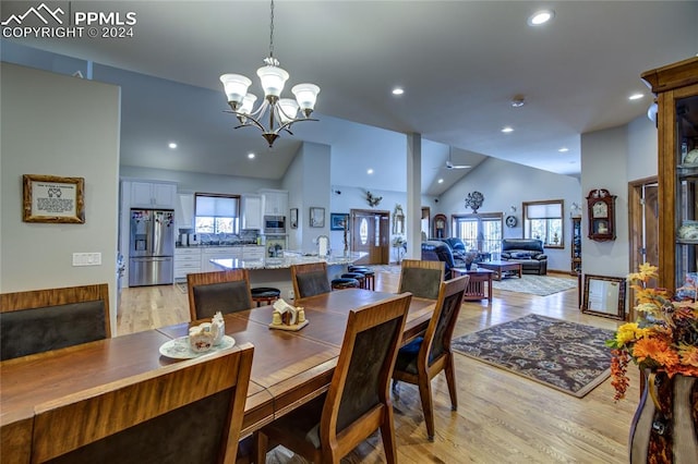 dining space featuring an inviting chandelier, high vaulted ceiling, and light hardwood / wood-style flooring