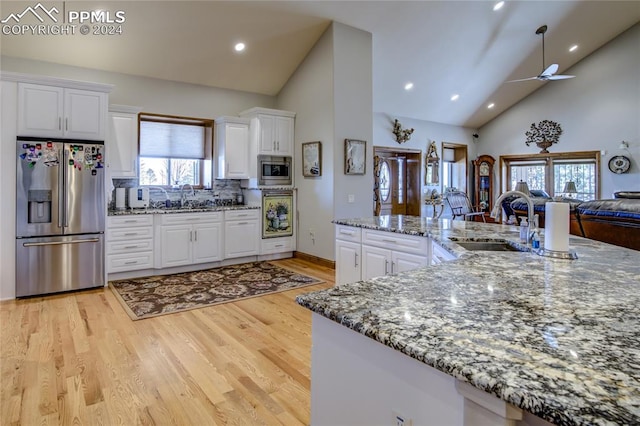 kitchen featuring ceiling fan, white cabinets, stainless steel appliances, high vaulted ceiling, and light wood-type flooring