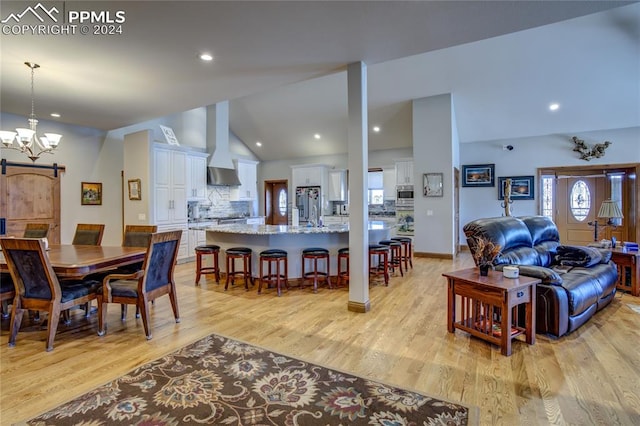 dining area with an inviting chandelier, high vaulted ceiling, and light hardwood / wood-style floors