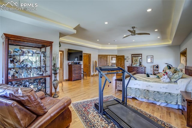 bedroom with a tray ceiling, ceiling fan, and light wood-type flooring