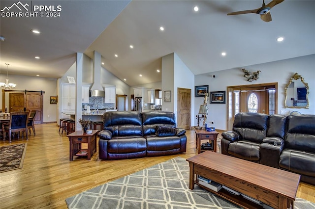 living room with a barn door, high vaulted ceiling, ceiling fan with notable chandelier, and light wood-type flooring