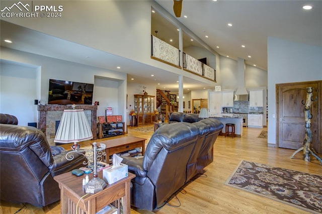 living room featuring ceiling fan, light hardwood / wood-style floors, and high vaulted ceiling