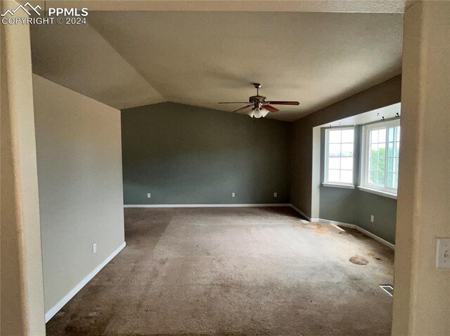 spare room featuring ceiling fan, carpet, and vaulted ceiling