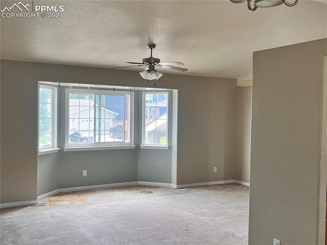 empty room with ceiling fan, carpet flooring, and a textured ceiling