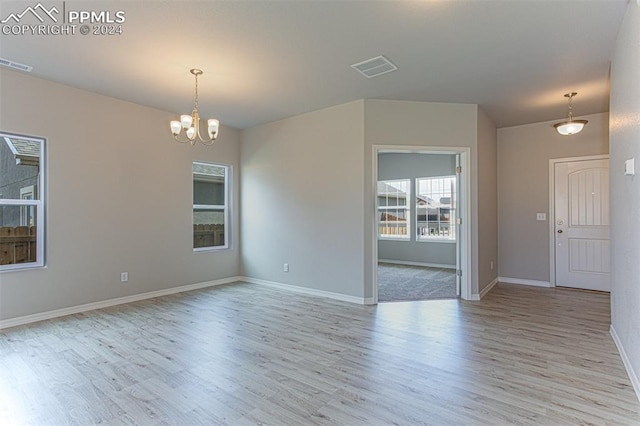 empty room featuring light hardwood / wood-style floors and an inviting chandelier