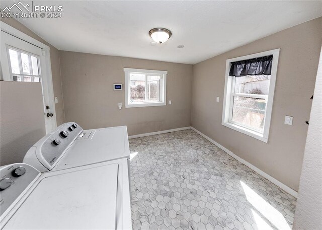 laundry room with plenty of natural light, light tile flooring, and washing machine and dryer