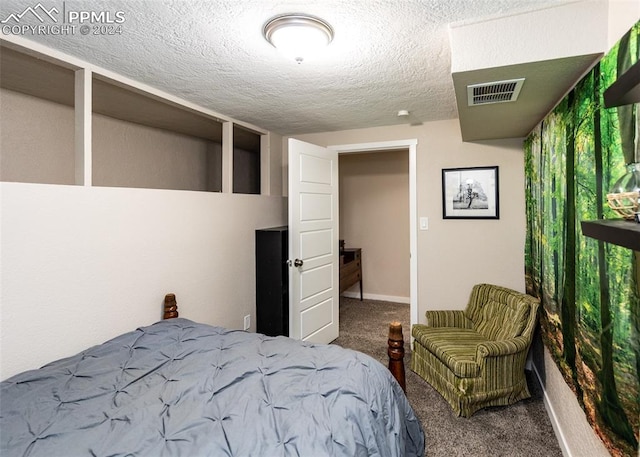 bedroom with a textured ceiling and dark colored carpet