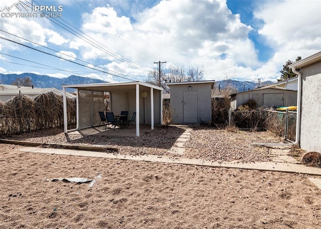 rear view of property with an outdoor structure, a patio area, and a mountain view